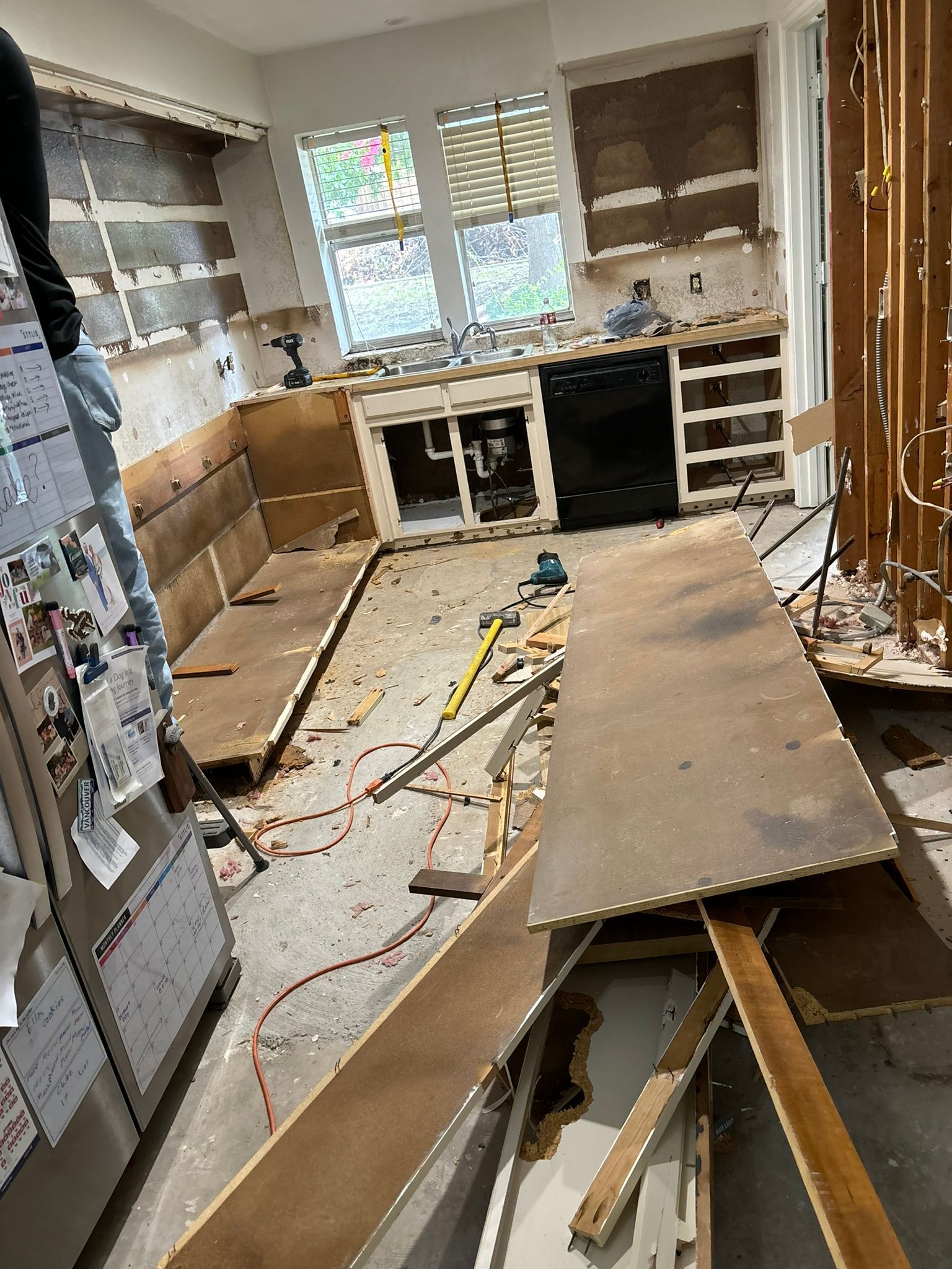 A dirty under construction kitchen with wooden materials on the ground