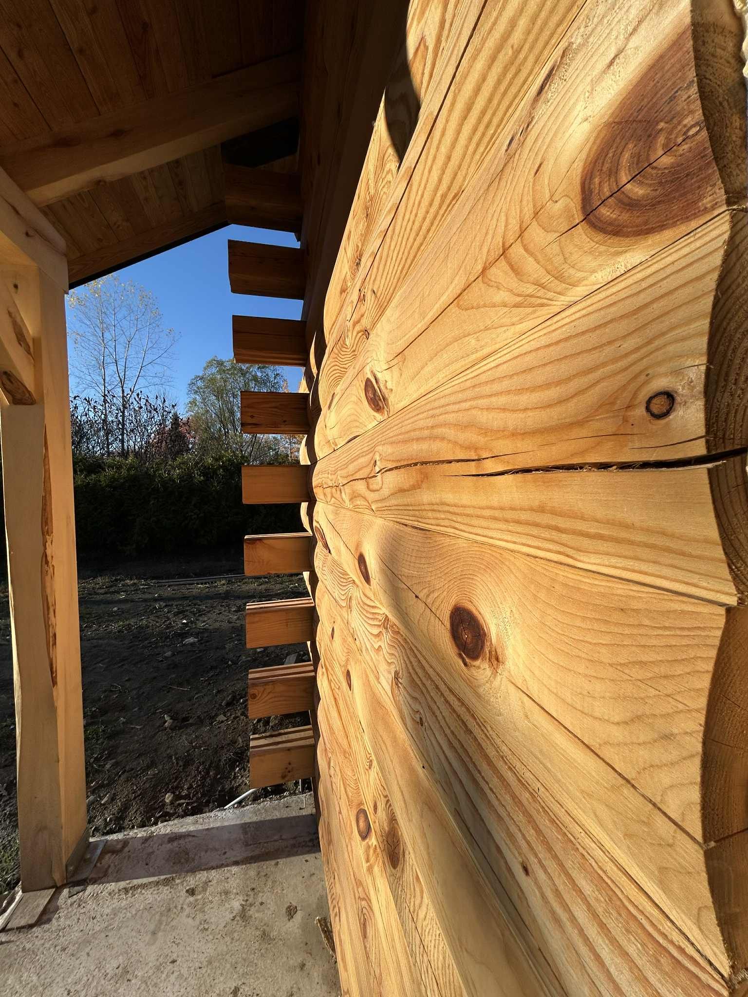 Détail d'un mur de cabane en rondins de bois, mettant en valeur les rondins superposés et les joints à encoches. Cadre extérieur ensoleillé.