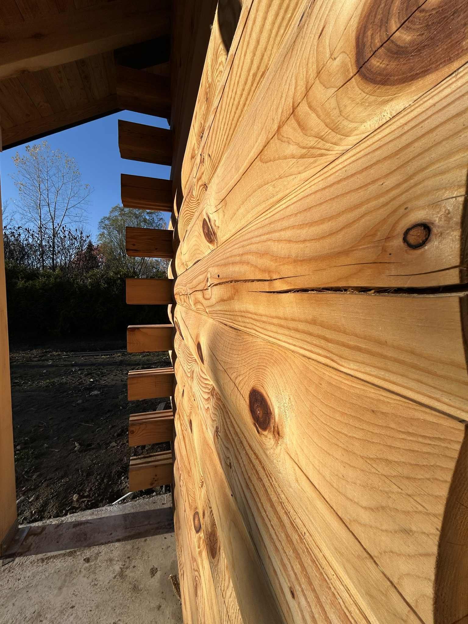 Gros plan sur un angle de construction en bois montrant la structure en rondins avec encoches. Cadre extérieur ensoleillé.