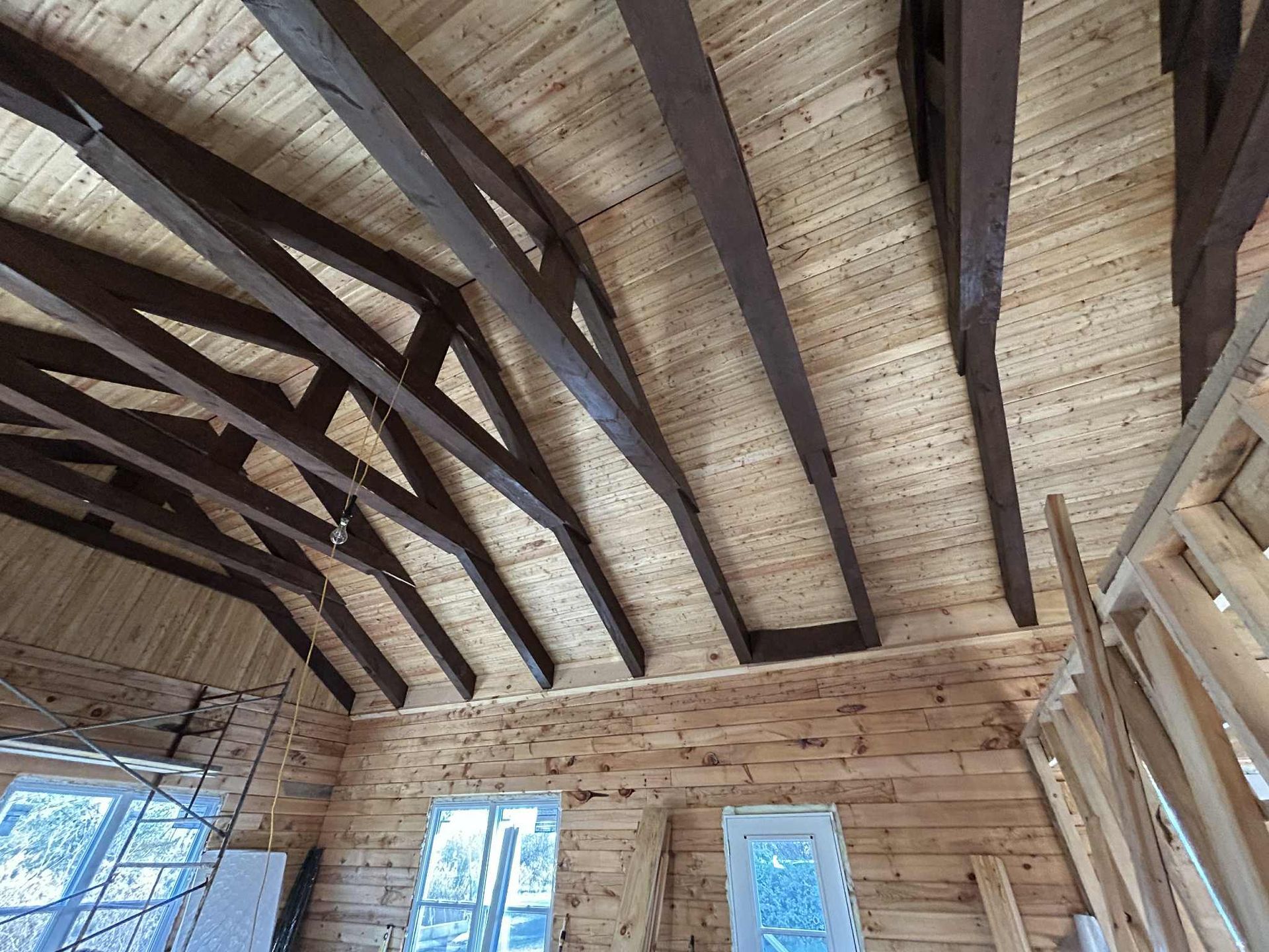 Plafond en bois avec poutres brun foncé et planches de bois clair.