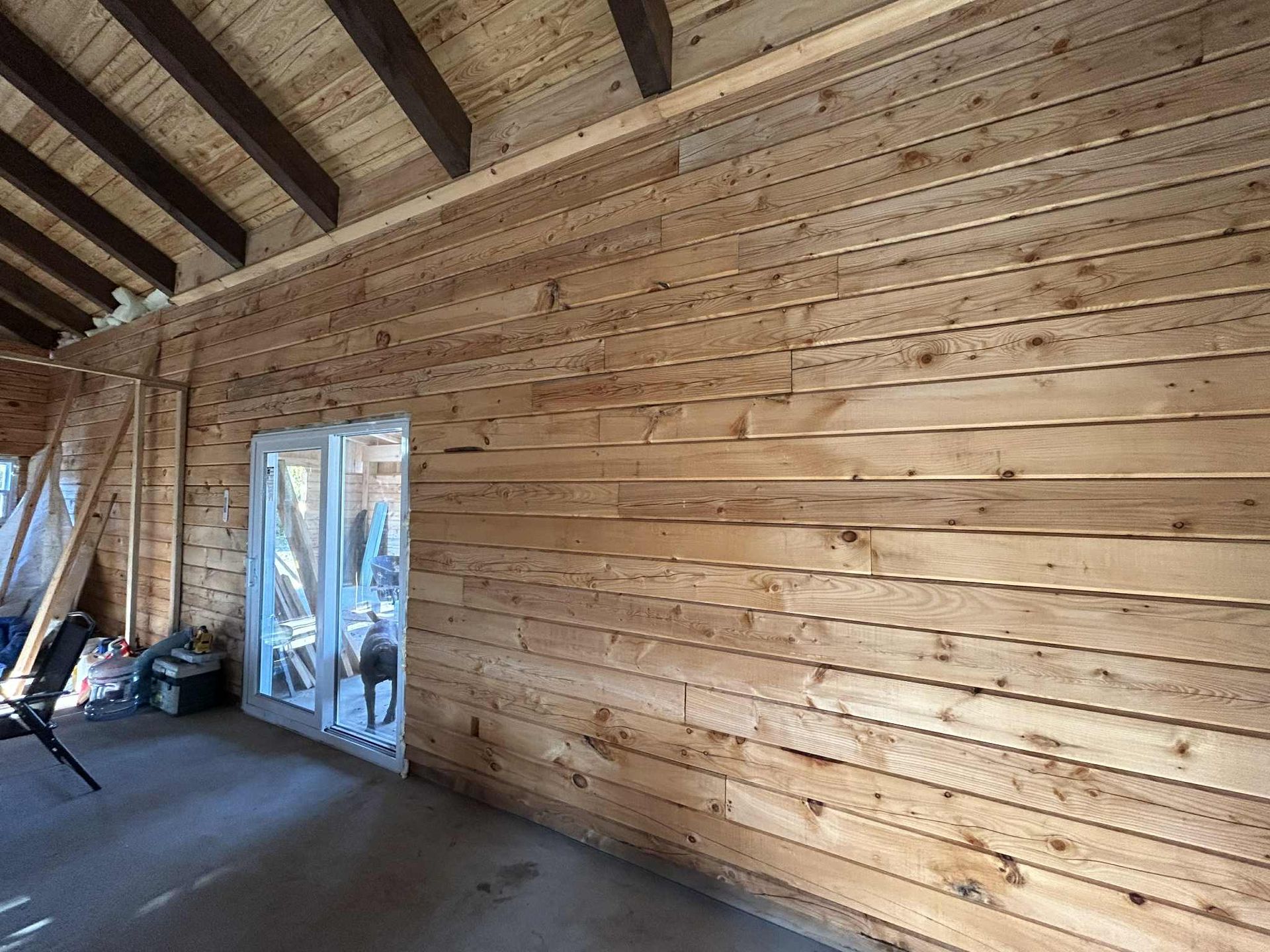 Intérieur en bois avec une porte et des poutres apparentes au plafond.