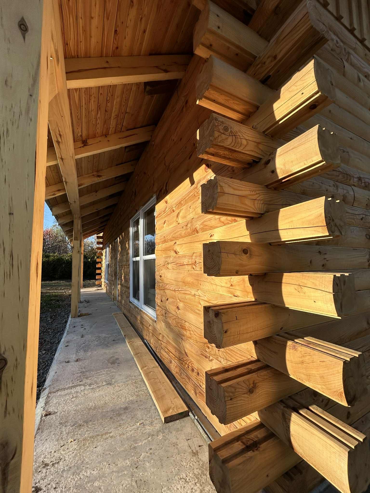 Cabane en rondins en construction, avec rondins apparents et porche.