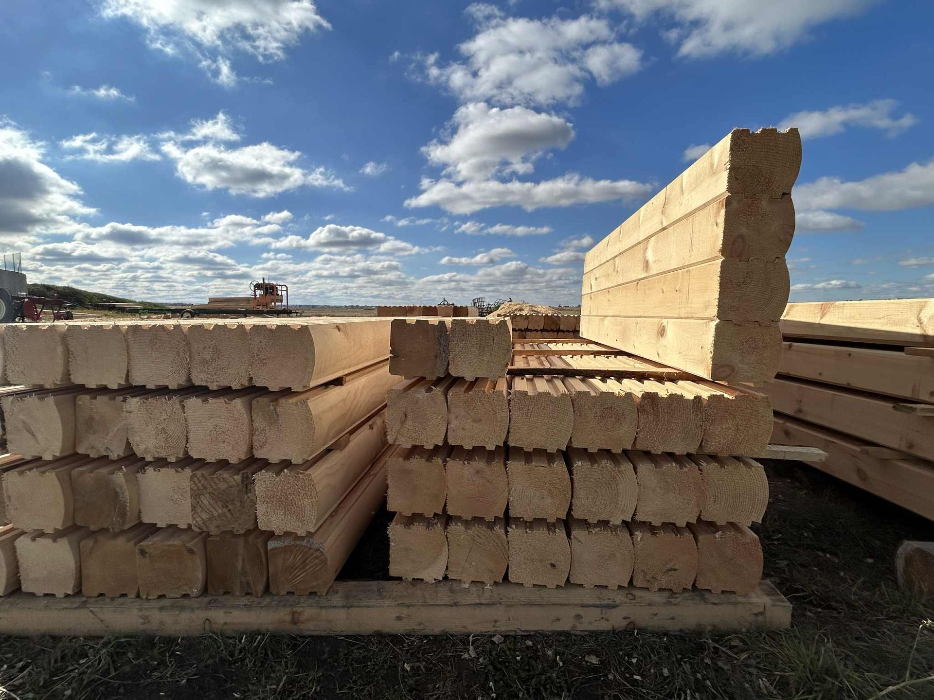 Des piles de blocs de construction en bois emboîtables, à l'extérieur, sous un ciel nuageux.