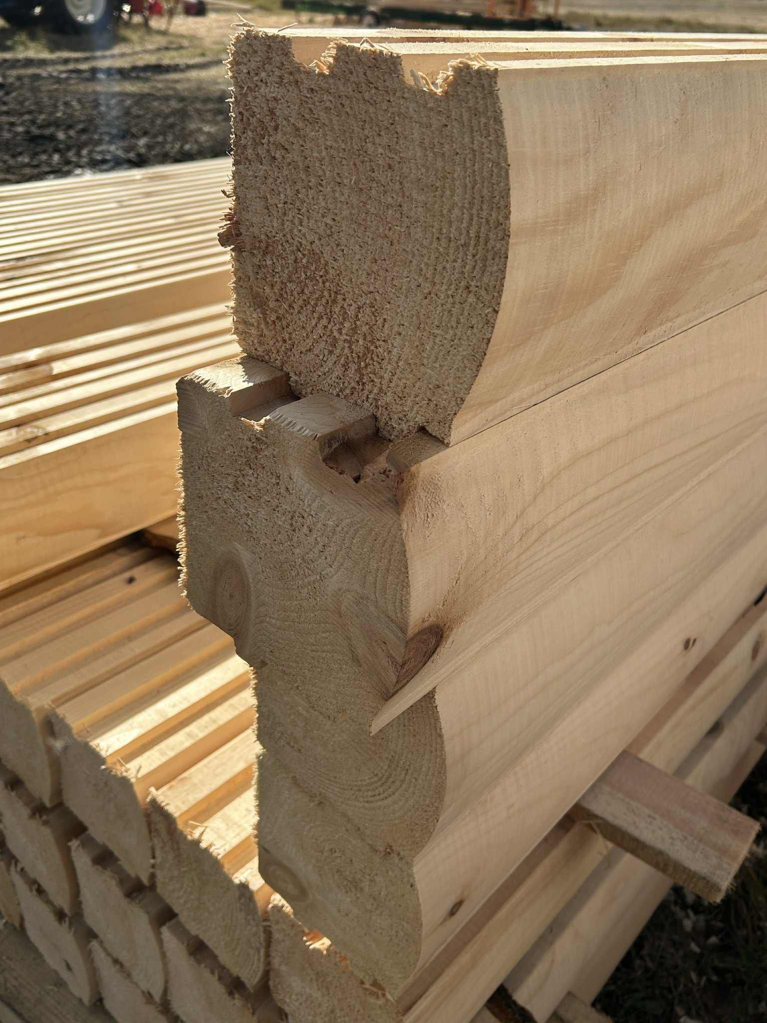Gros plan sur des poutres en bois imbriquées, présentant une partie supérieure arrondie et entaillée et une base carrée.