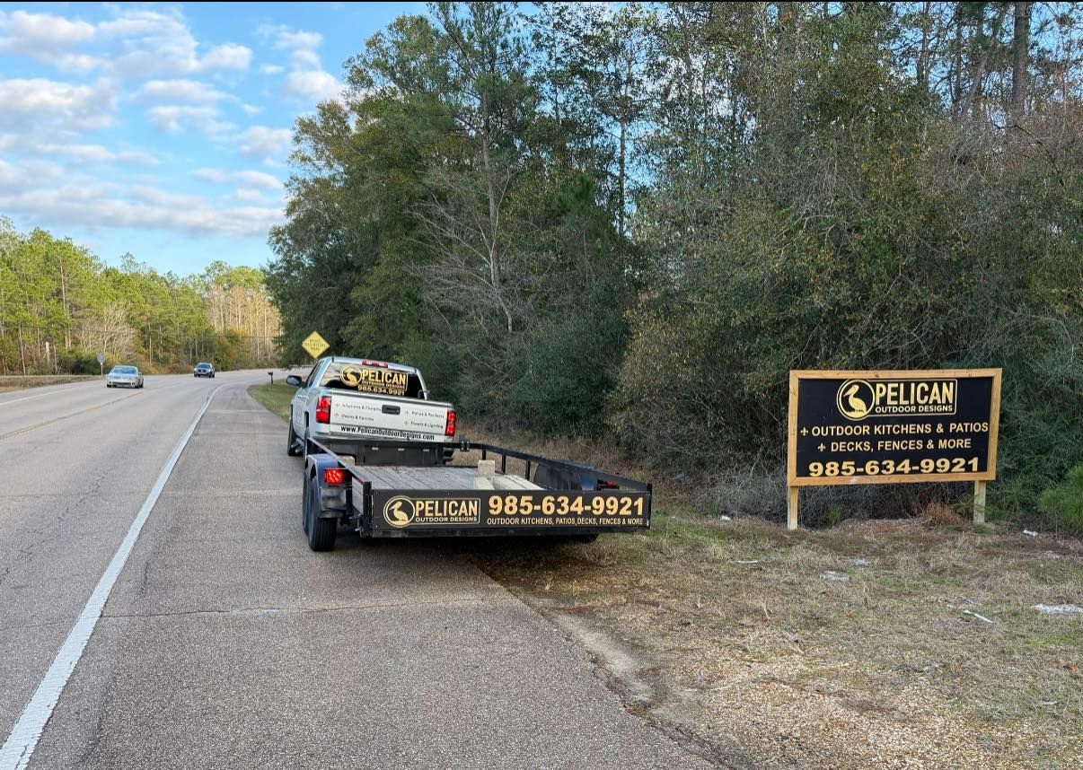 Roadside tow truck beside a black-and-gold sign along a wooded highway shoulder