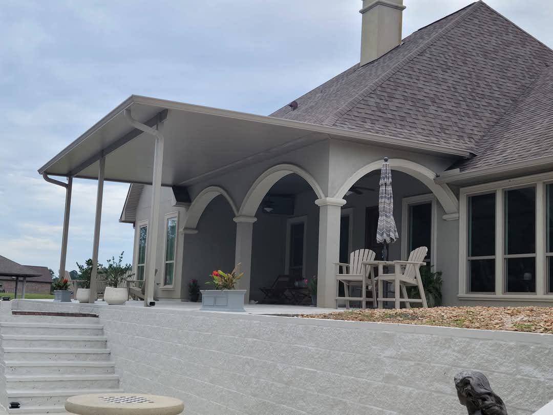 Modern white house patio with arched porch, gray roof, and outdoor dining set overlooking steps.
