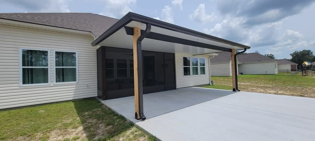 Single-story house exterior with a covered patio and white siding under a cloudy sky
