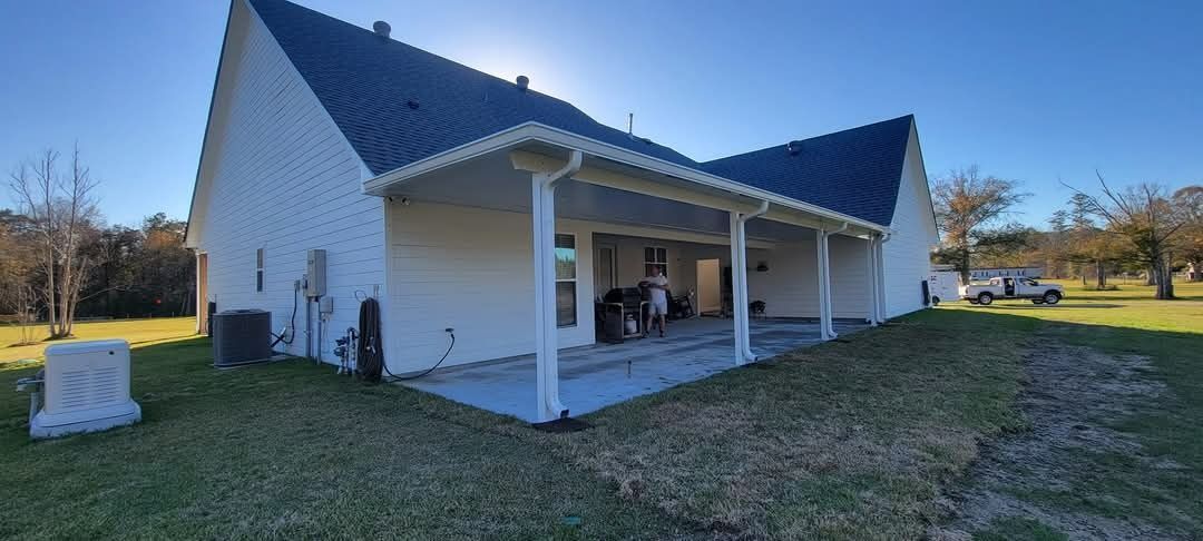 White house with a blue roof and covered porch in a grassy yard on a sunny day