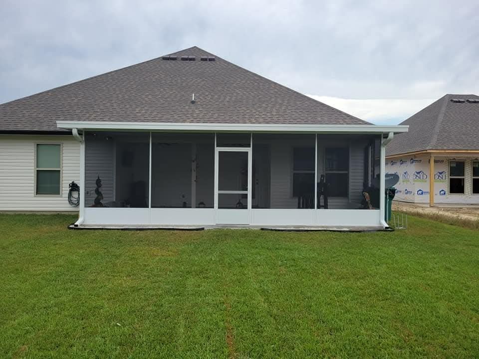 Single-story house with screened front porch and green lawn under cloudy sky