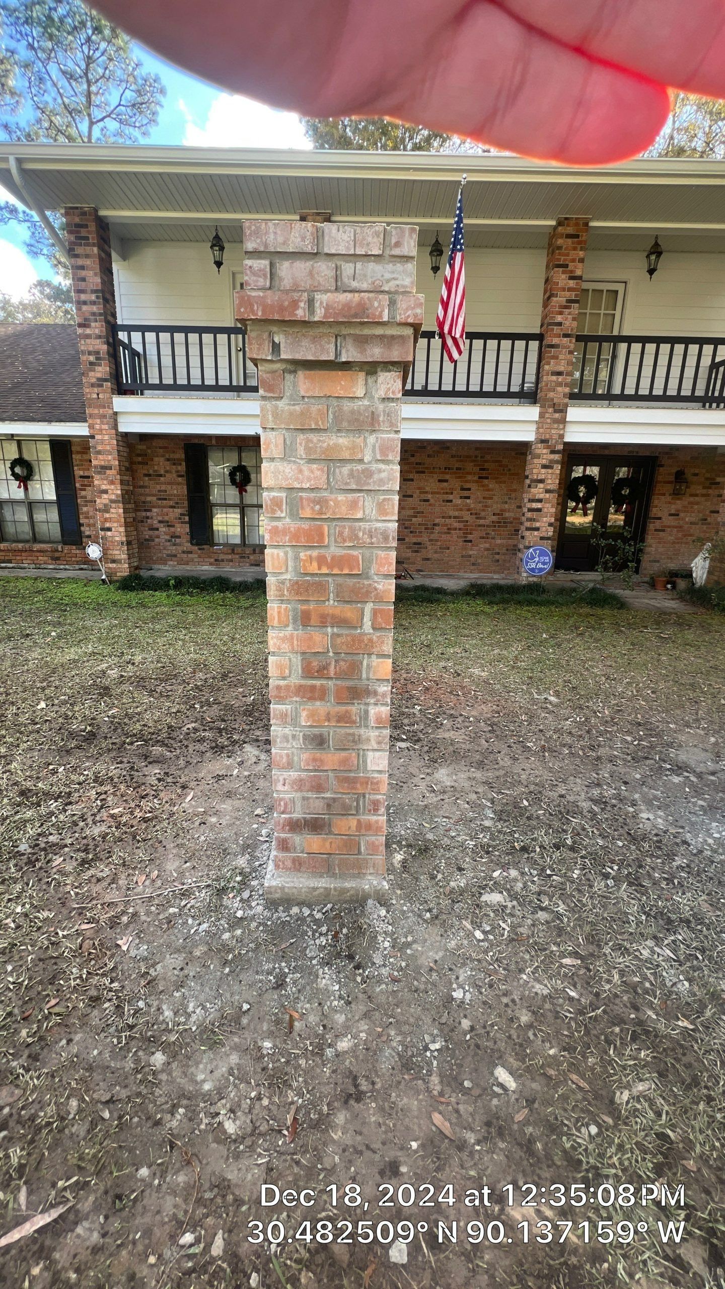 Brick porch column supporting a covered patio with a U.S. flag hanging in the background.