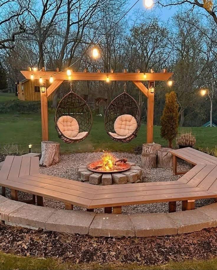 Cozy outdoor fire pit with curved wooden benches, hanging chairs, and string lights at dusk
