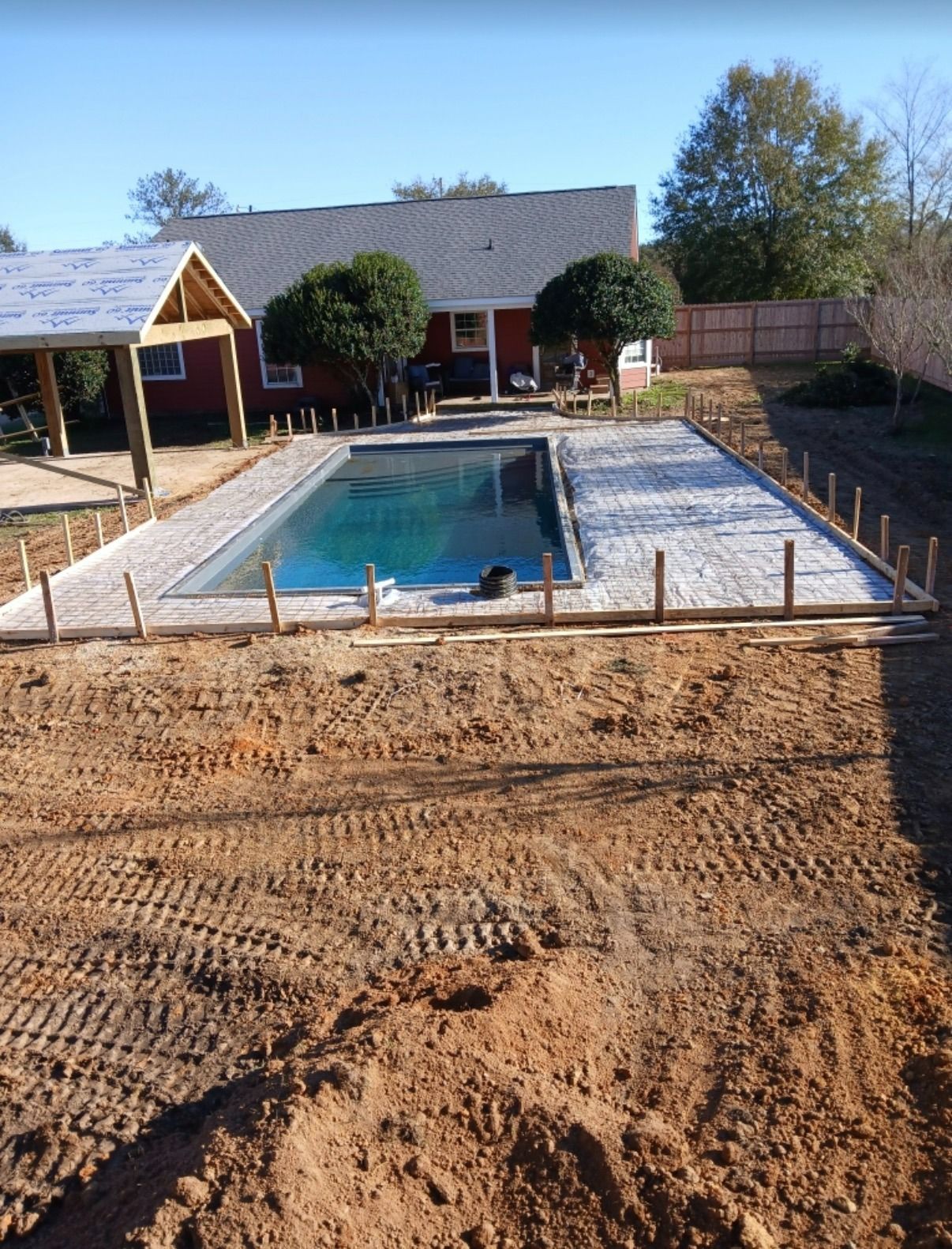 Backyard with rectangular swimming pool, patio, and fresh dirt landscaping in front