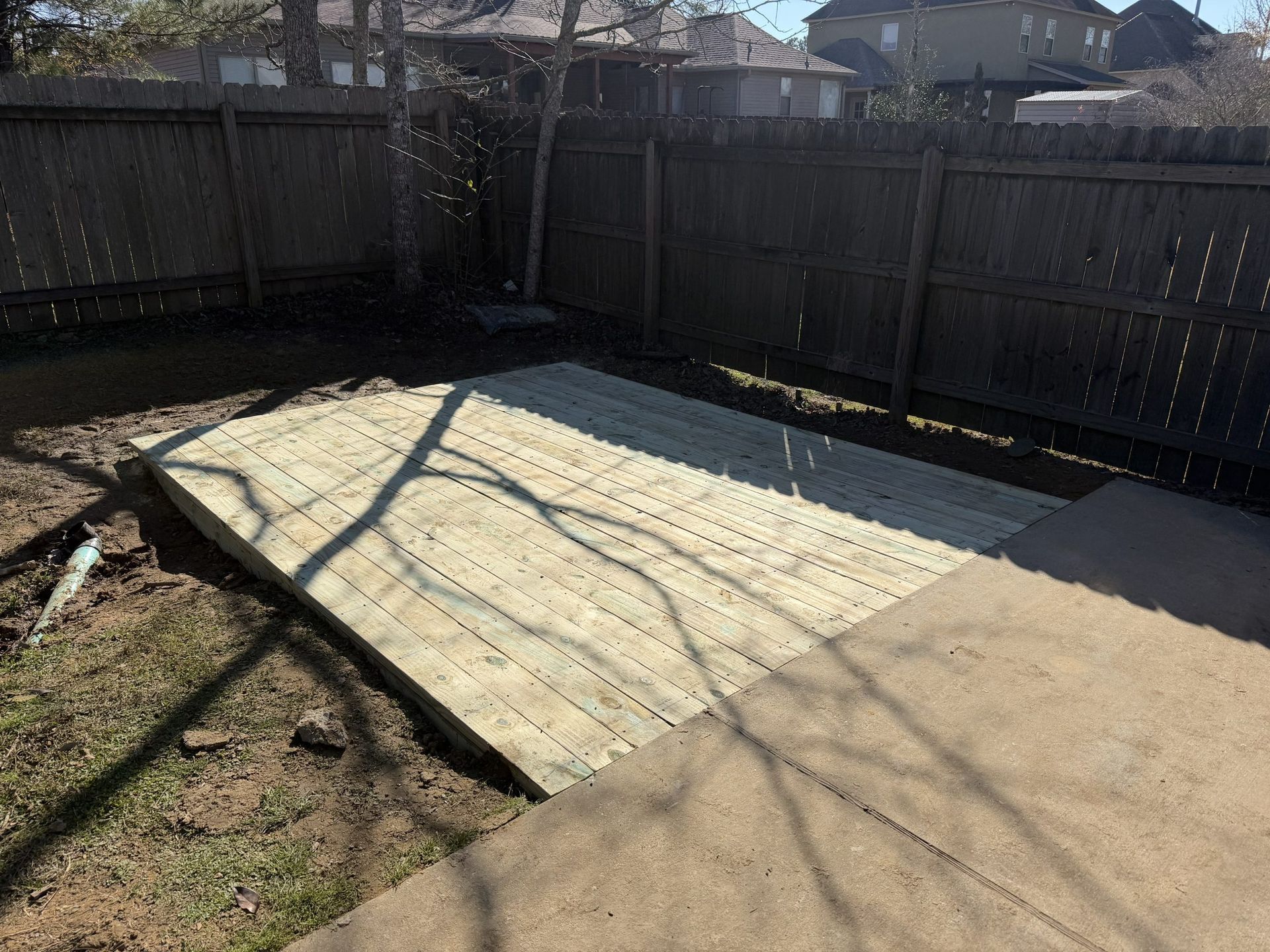 Backyard with a large white tarp-covered rectangular area beside a fence and deck