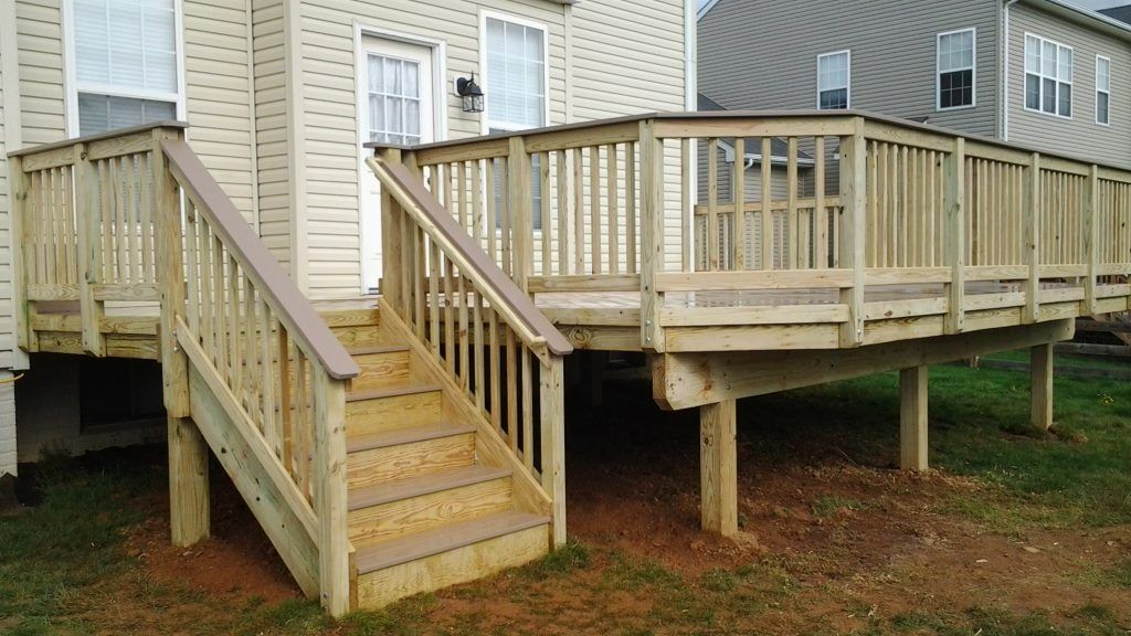 Wooden accessibility ramp with railings and stairs beside a beige house
