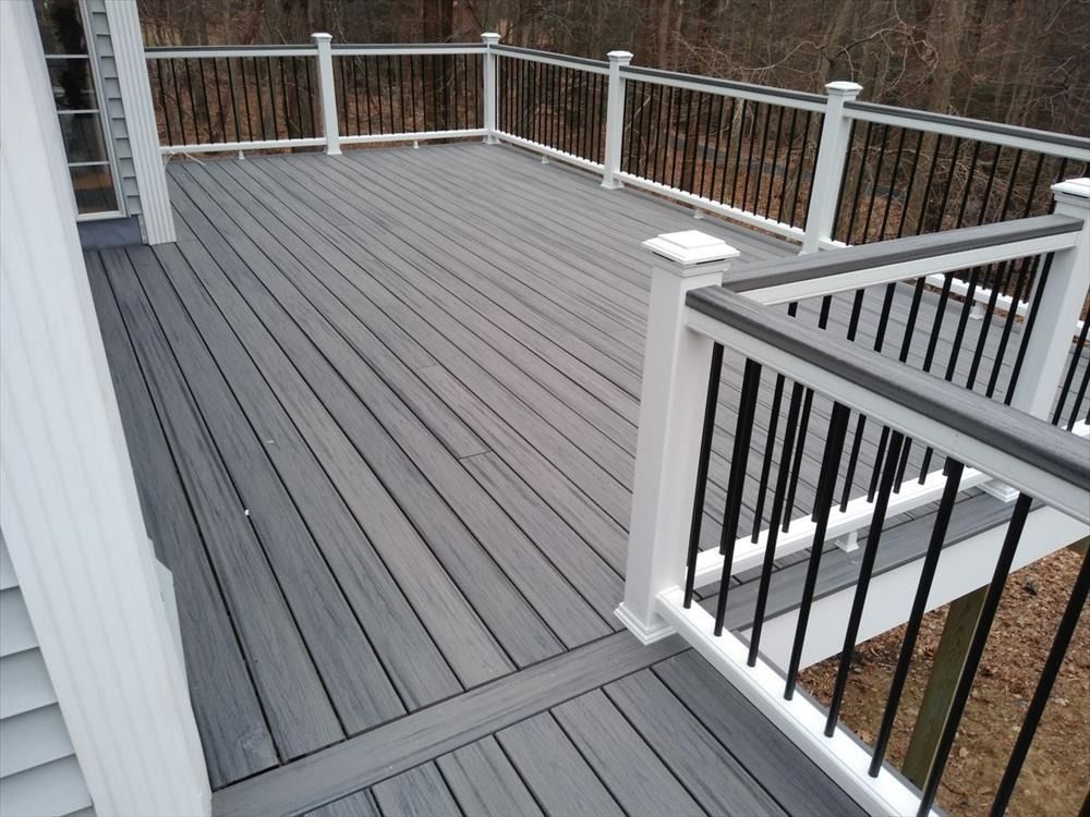 Gray composite deck with white railings and black balusters overlooking a wooded yard