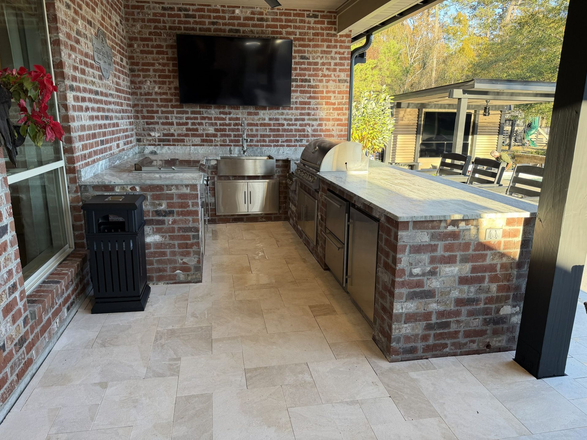 Covered brick patio with outdoor kitchen, TV, grill, and seating area