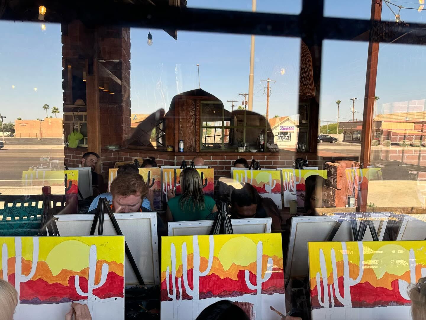 People seated at a cafe window with colorful mural art and an urban street view outside