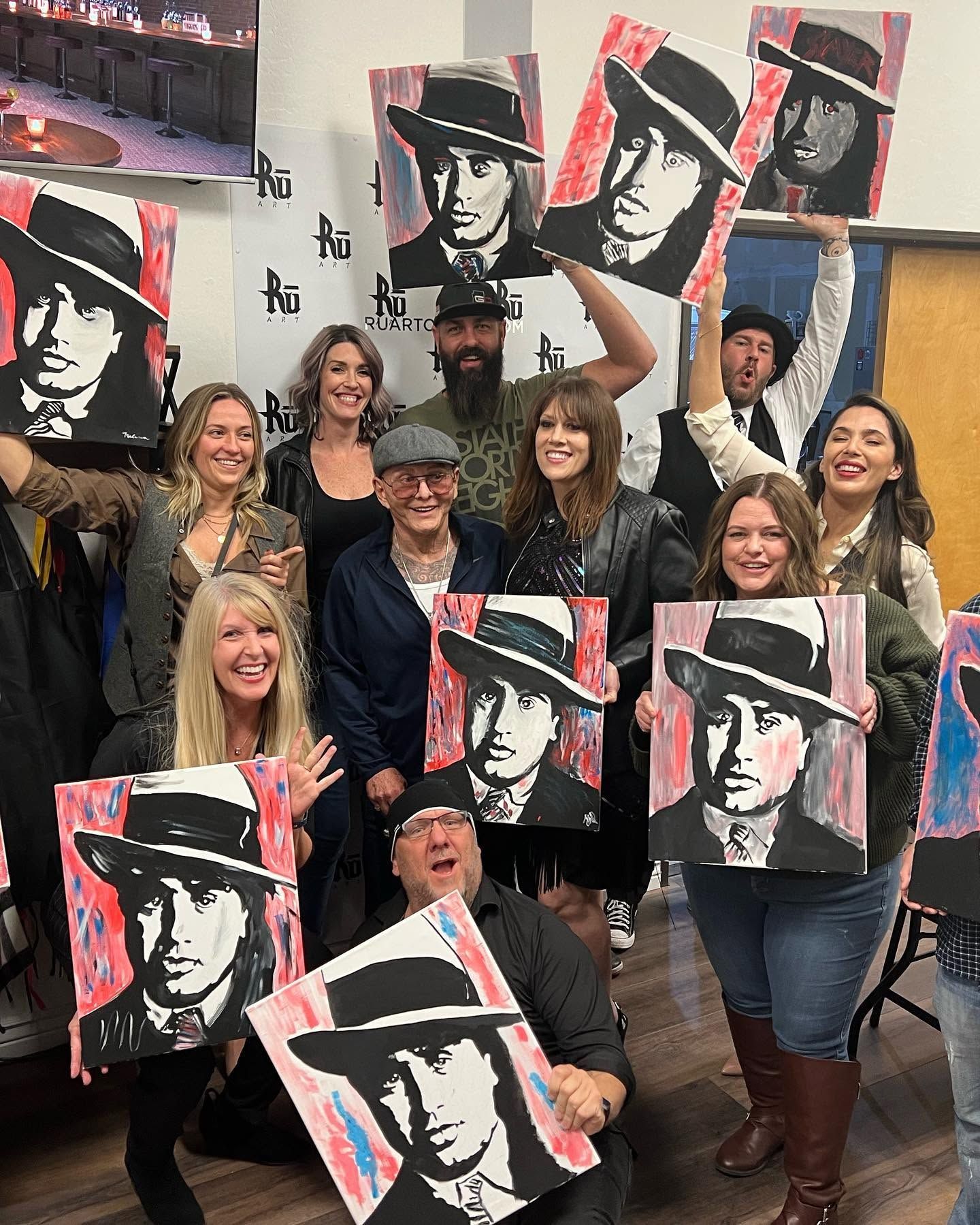 Group holding pop-art posters in a classroom, smiling and posing together