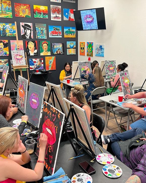 Art class with students painting colorful canvases on easels in a bright studio room
