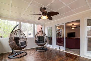 Screened porch with hanging egg chairs, ceiling fan, and brown tile floor
