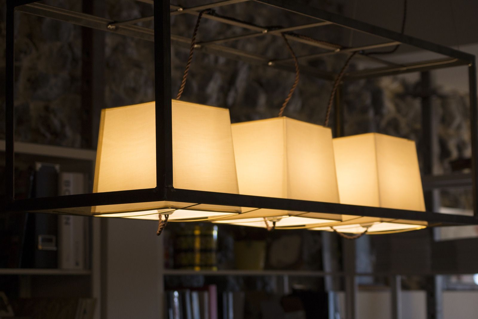 Three glowing cube pendant lights hanging in a dark room