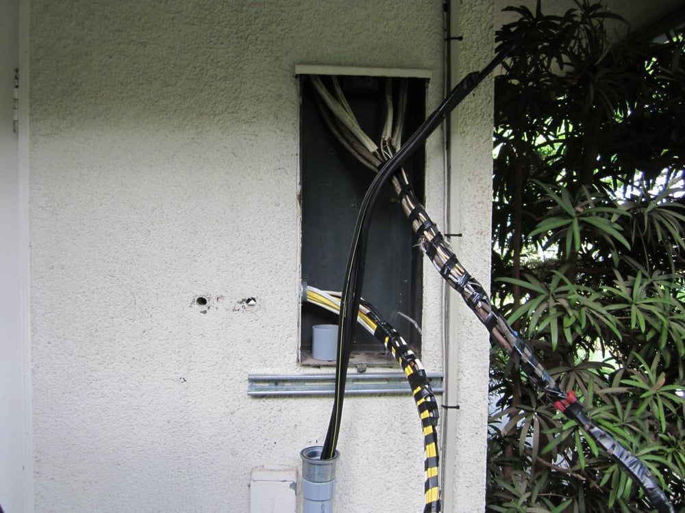 Tangled cables and hoses near a window on a house exterior wall