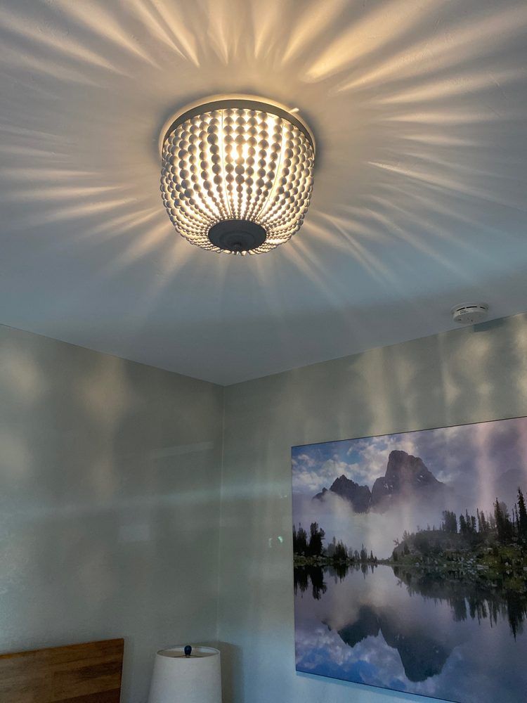Bedroom ceiling light casting starburst shadows over pale walls and mountain landscape wall art
