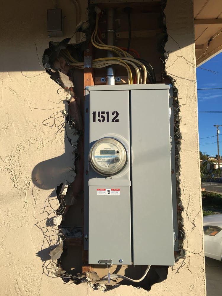 Electric meter and gray utility box mounted on a cracked wall, labeled 1512.