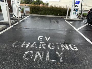 EV charging only parking space with white painted sign on dark pavement at a station