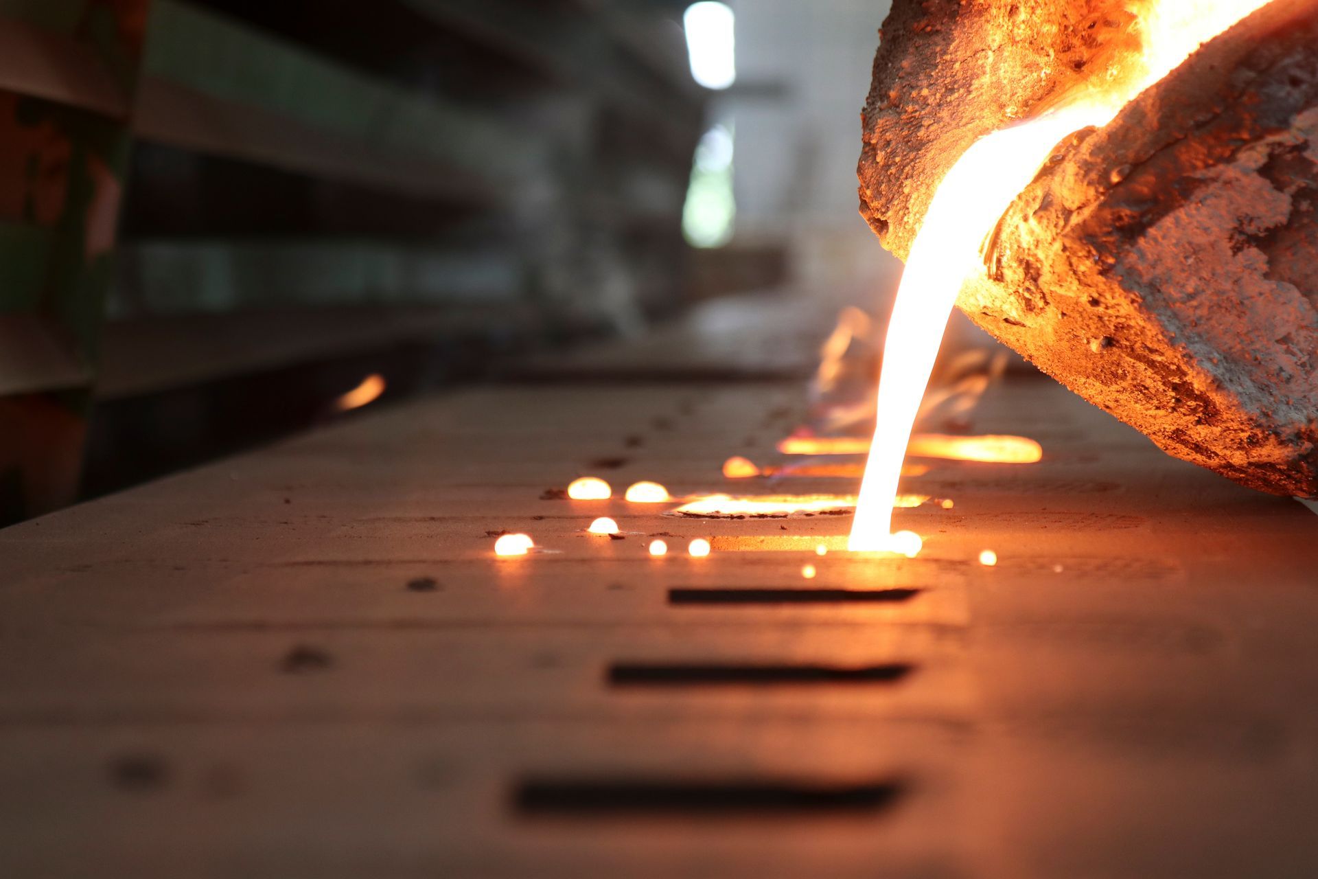 A close-up of the process of molten metal being poured into a mould.
