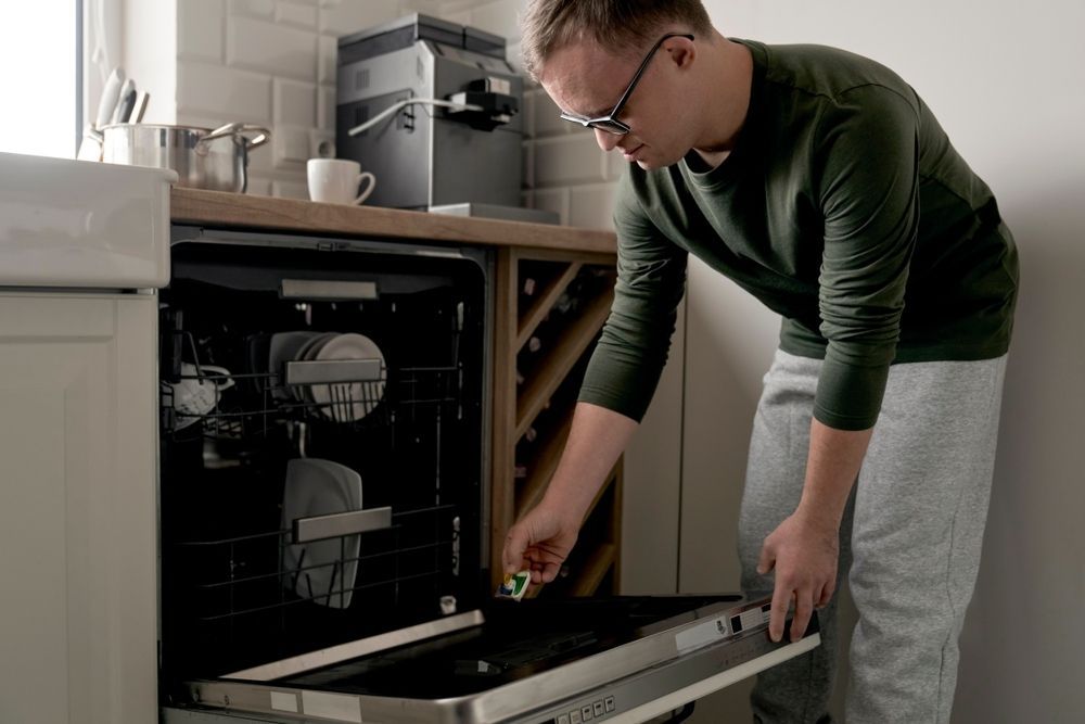 Young man with a disability packing a dishwasher - NDIS in Urangan, QLD