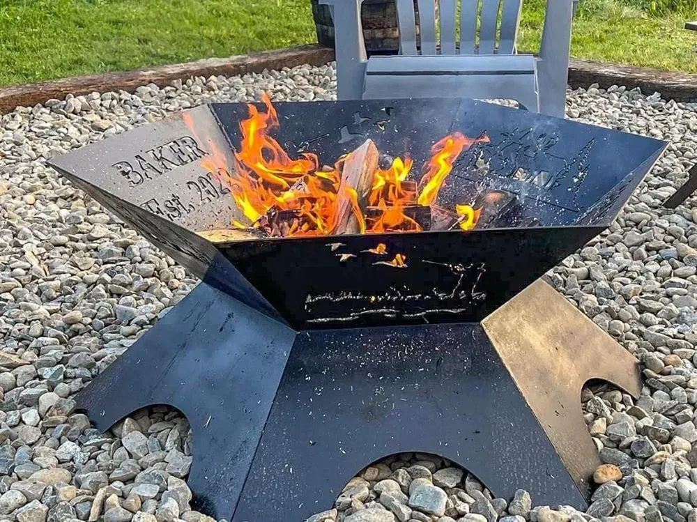 A fire pit is sitting on a pile of rocks next to a chair.
