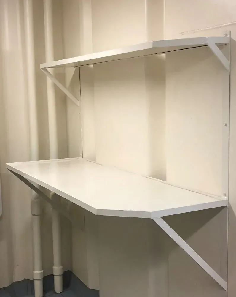 A white desk with a shelf above it in a room.
