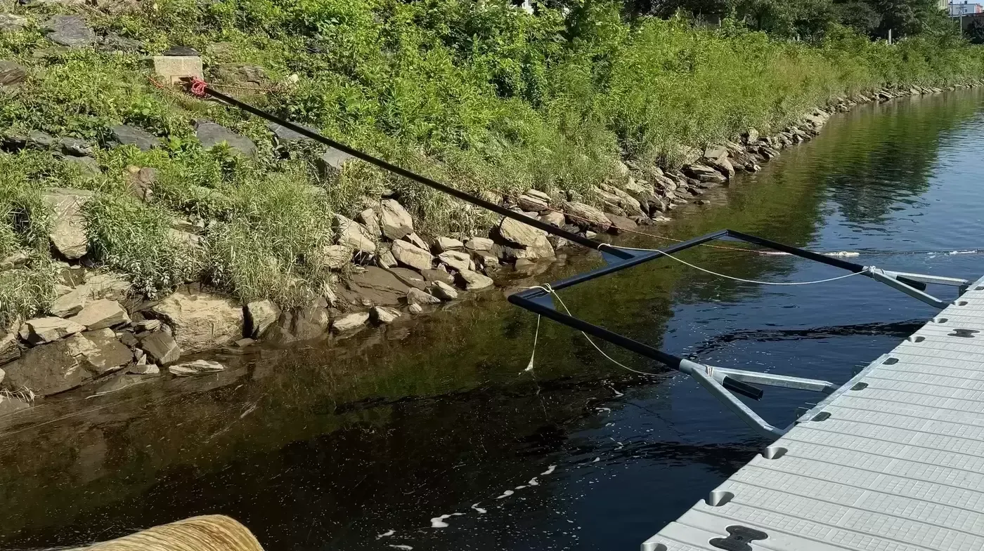 A person is fishing on a dock next to a river.