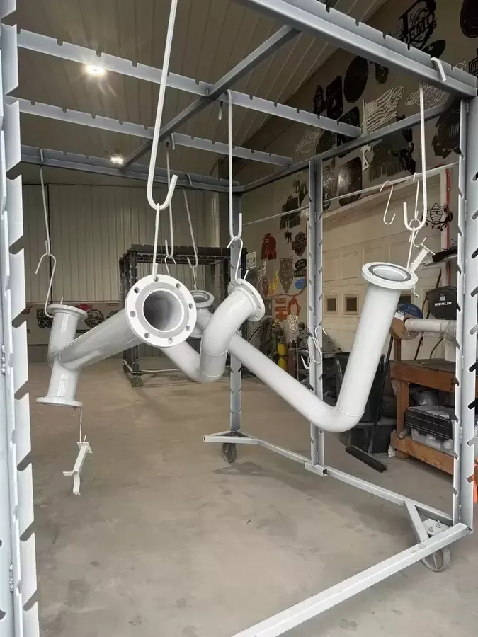 A bunch of white pipes are hanging from a rack in a room.