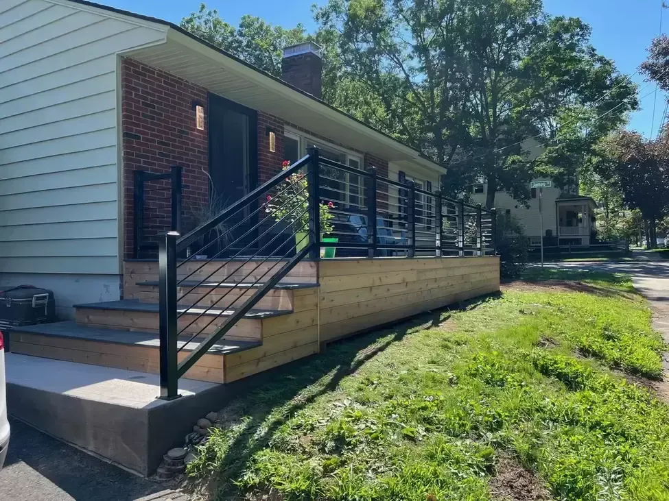 A house with a wooden deck and stairs in front of it.