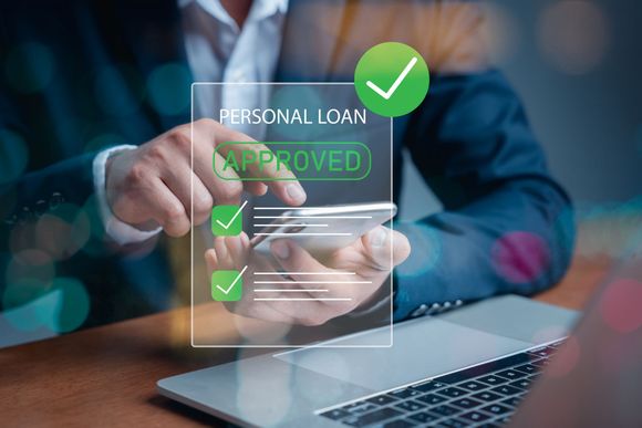 Hand pointing to a laptop with a “personal loan approved” digital overlay and green checkmarks