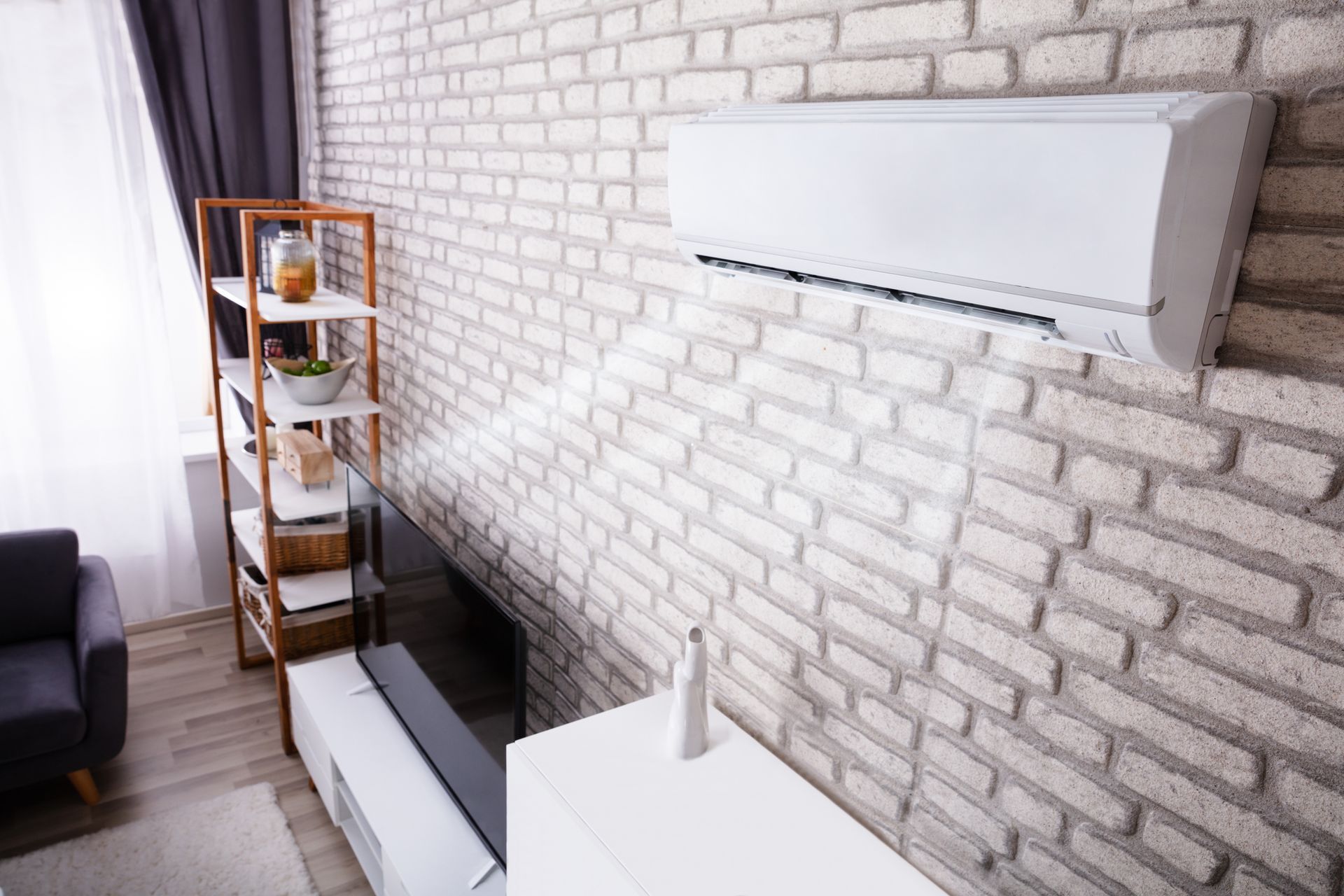Modern living room with white brick wall, TV, shelves, and curtains