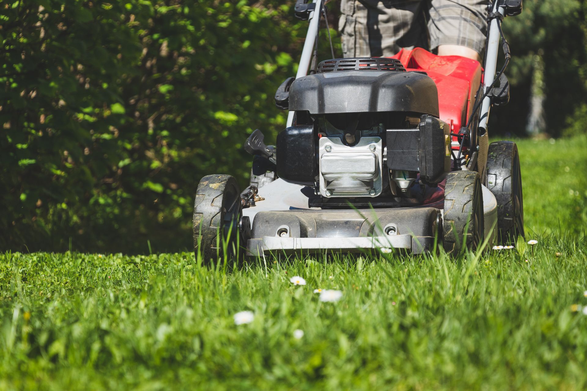 A man is mowing a lush green lawn with a lawn mower.