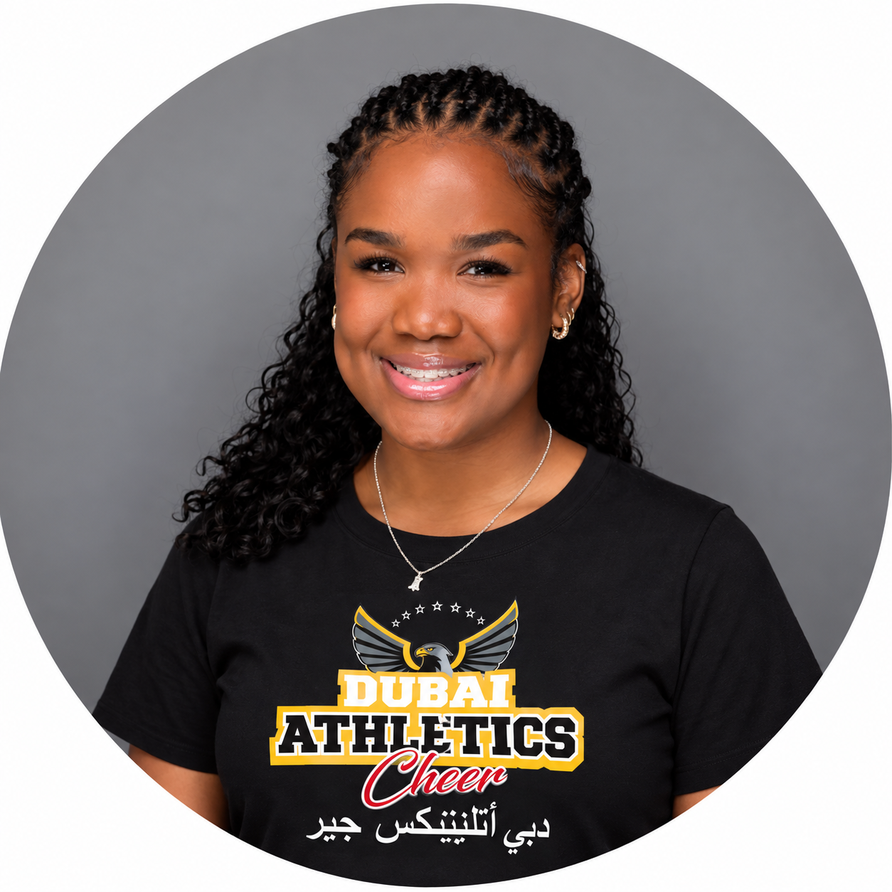 Woman wearing glasses and a gray Abu Dhabi Athletics Cheer t-shirt, smiling.