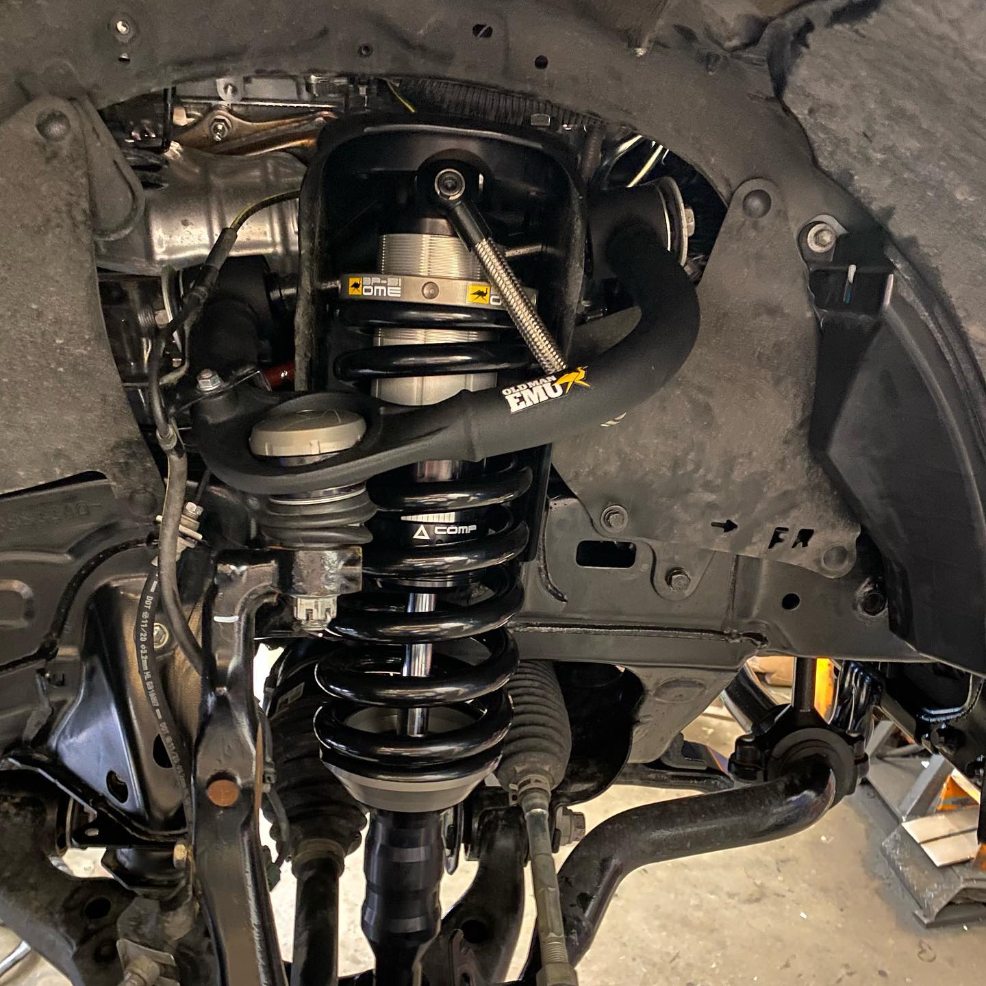 Suspension and shock absorber system of a vehicle, visible under the fender. Black components with yellow accents.