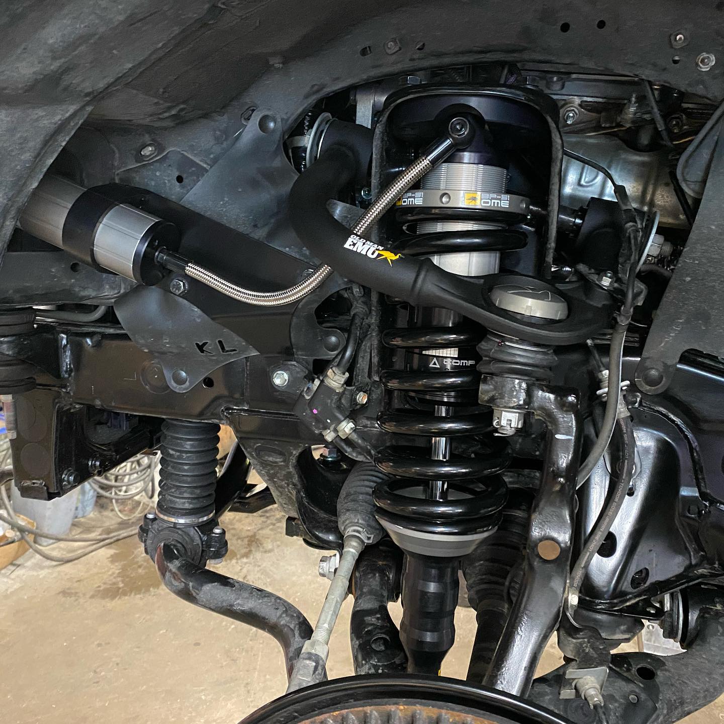 Black vehicle suspension system, including shock absorber and coil springs, with metallic components.