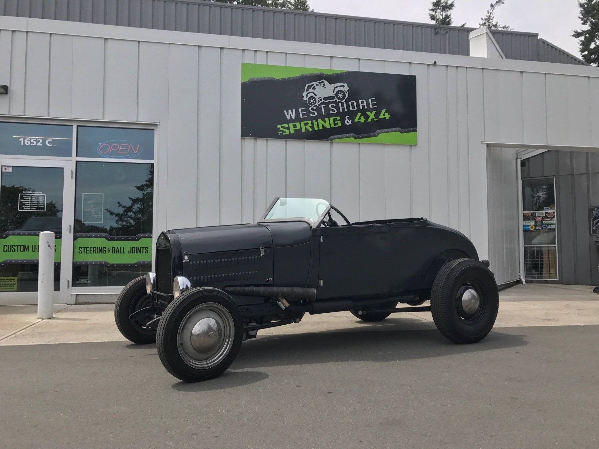 Black vintage car parked outside a building with the sign