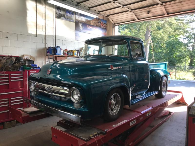 Teal vintage Ford pickup truck on a red lift in a garage.