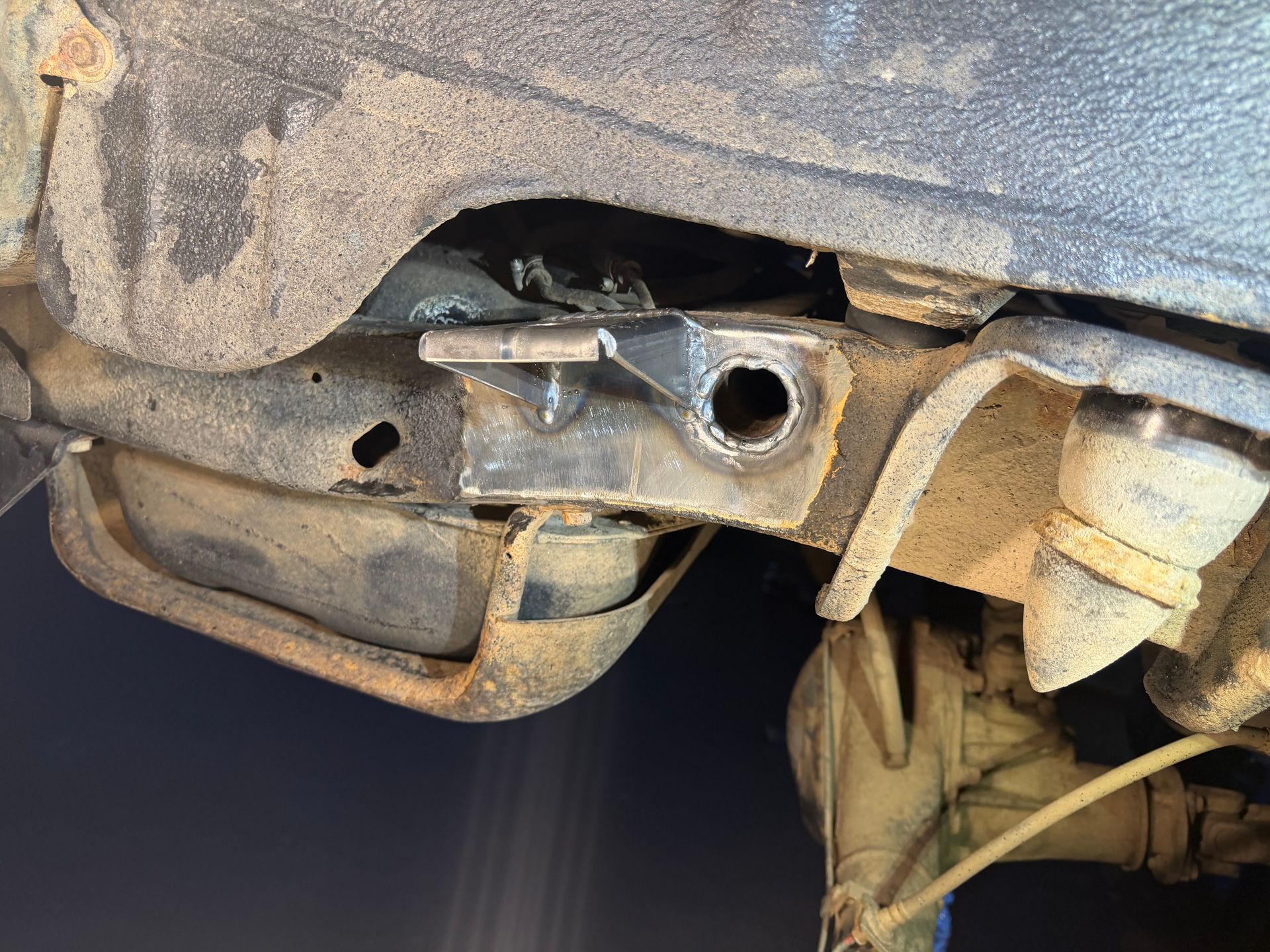 Metal vehicle suspension component, with a circular hole, welded to frame.