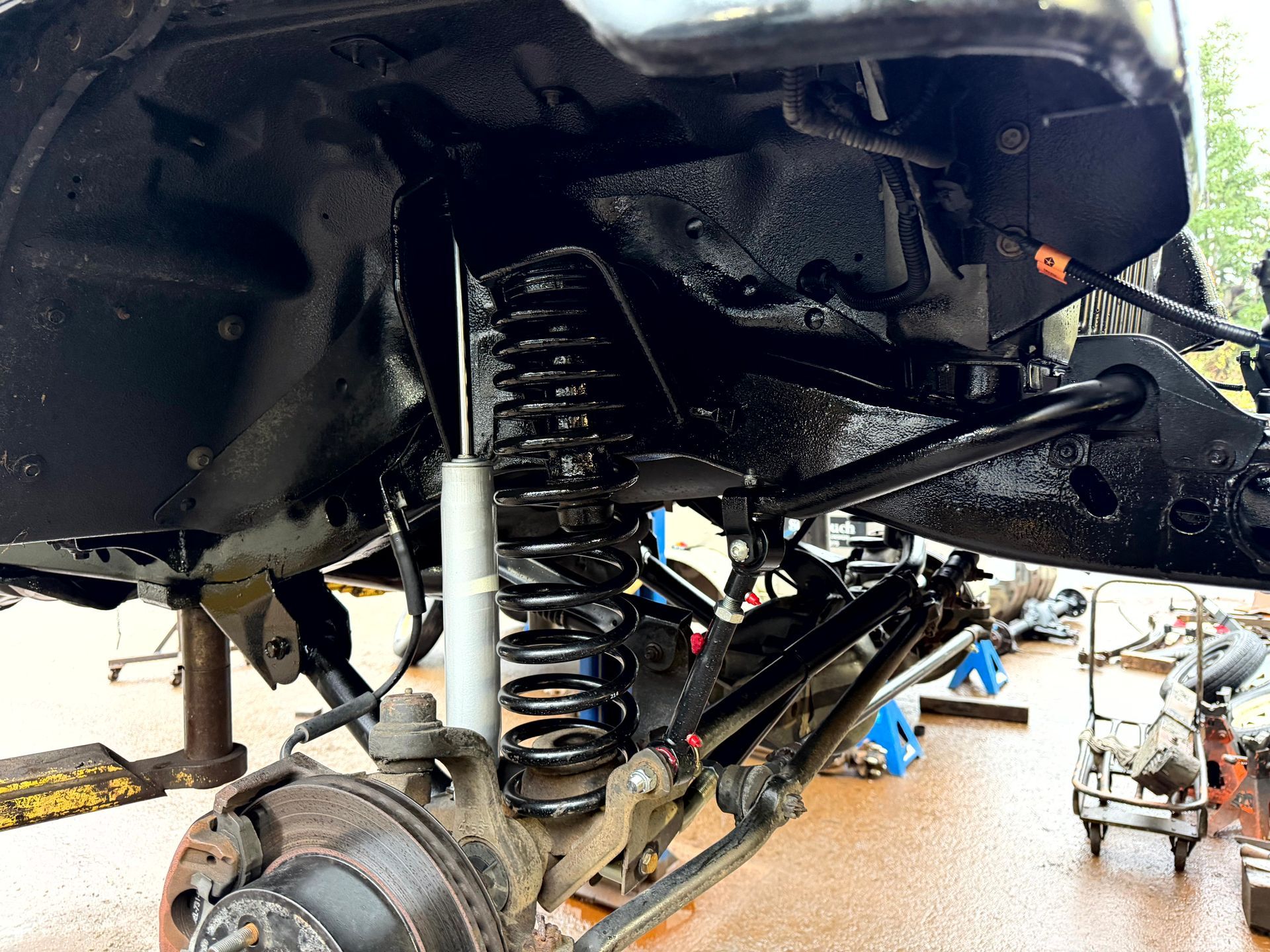 Black suspension system of a vehicle, including spring, shock, and control arms.