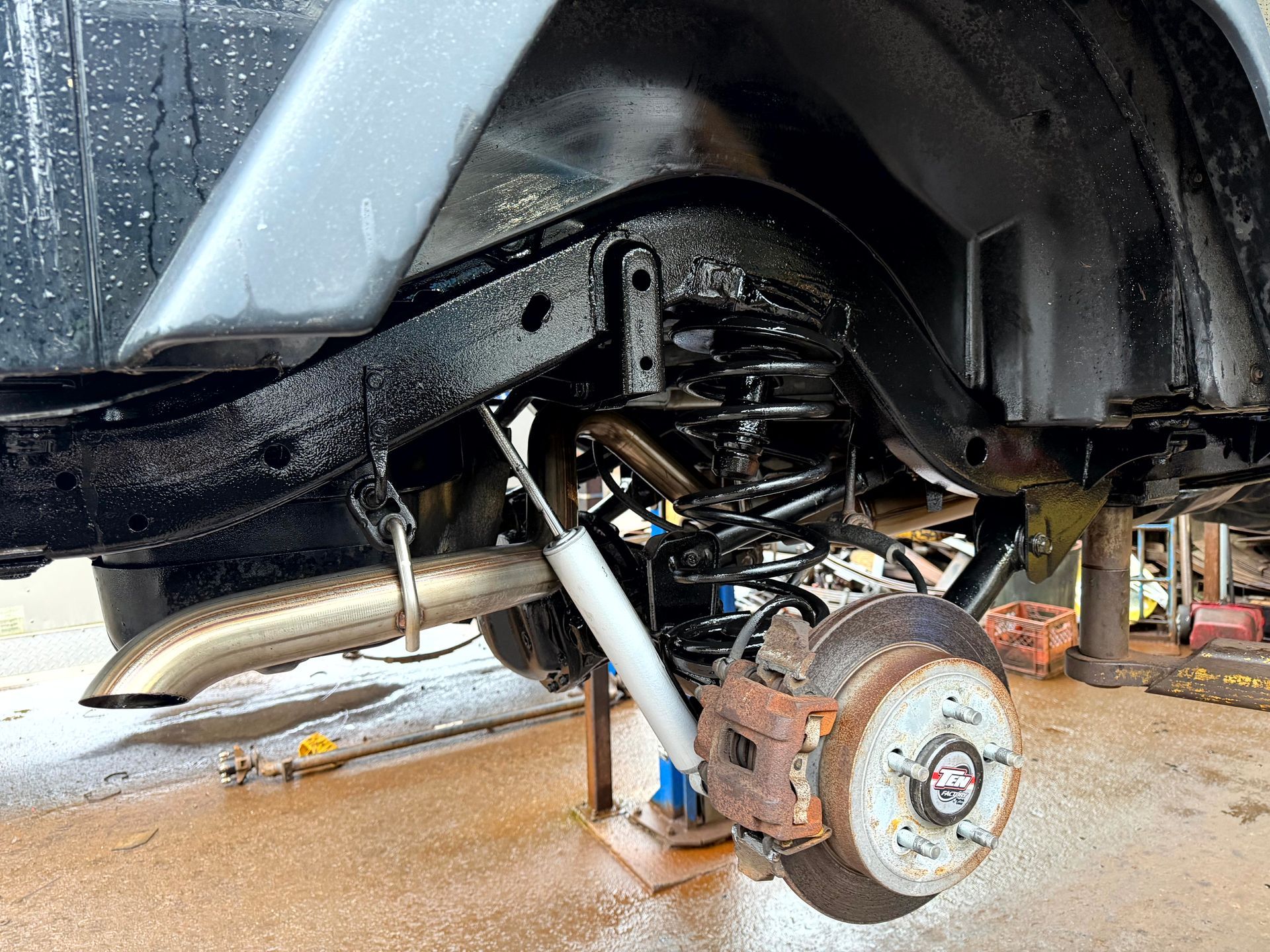 Black Jeep suspension and wheel assembly; vehicle repair underway.