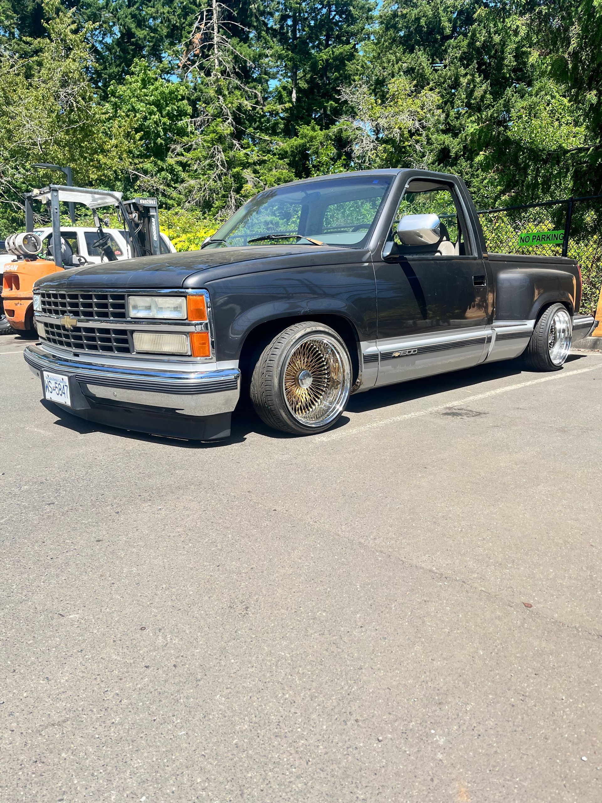 Black lowered Chevrolet pickup truck with gold wheels parked outside.