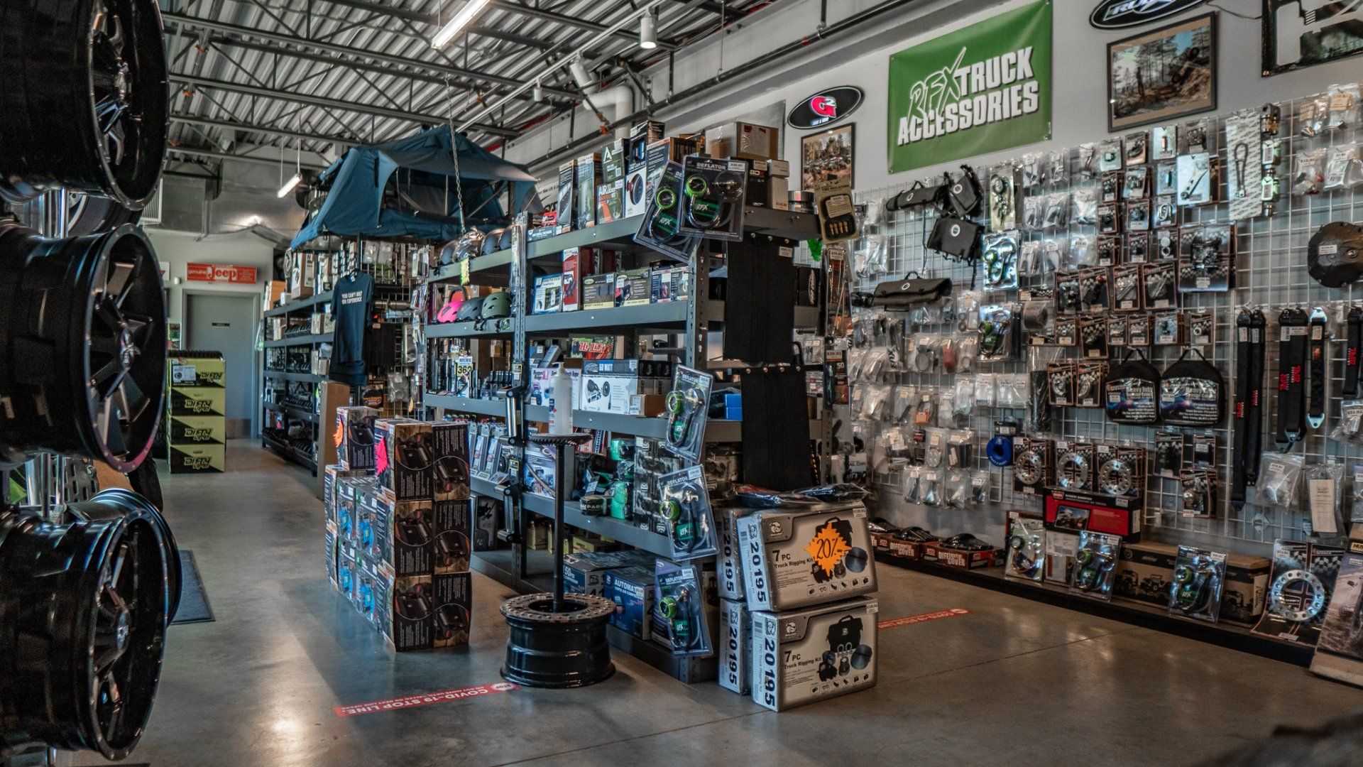 Interior of an auto parts store with wheels on display, shelves of products, and signage.