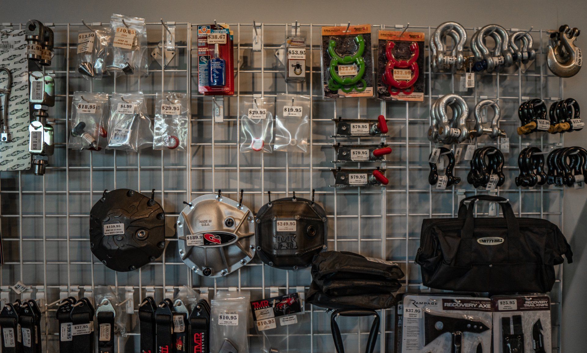 Display of automotive parts, including recovery gear and differential covers, on a wire grid wall.